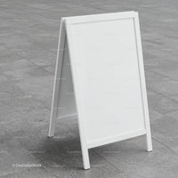 Blank white sandwich board sign on gray pavement