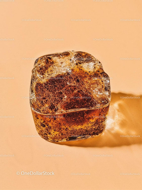 Zbliżenie na topniejącą brązową kostkę lodu na pastelowej powierzchni
