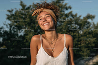 Young Woman Smiling Outdoors With Layered Necklaces and Headband