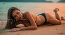 Elegant Woman in Black Bikini Lying on Beach at Sunset