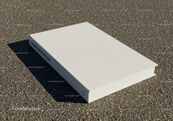 White hardcover book resting on textured asphalt surface JPG Mockup Image