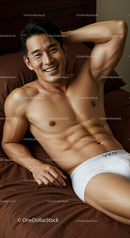 Smiling man relaxing on bed in white underwear