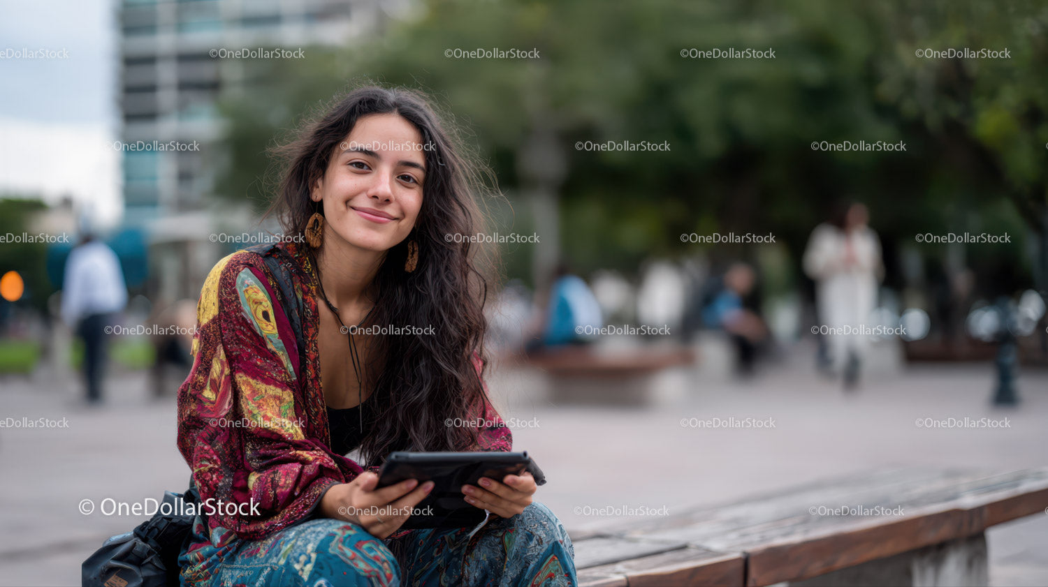 Young Woman with Long Curly Hair Sitting on Park Bench Using Tablet