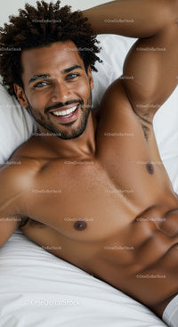 Smiling man relaxed on bed with curly hair
