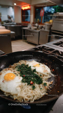 Fried Egg Noodles with Greens in a Black Skillet Ready to Serve