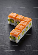 Fresh salmon and avocado sushi rolls on black slate
