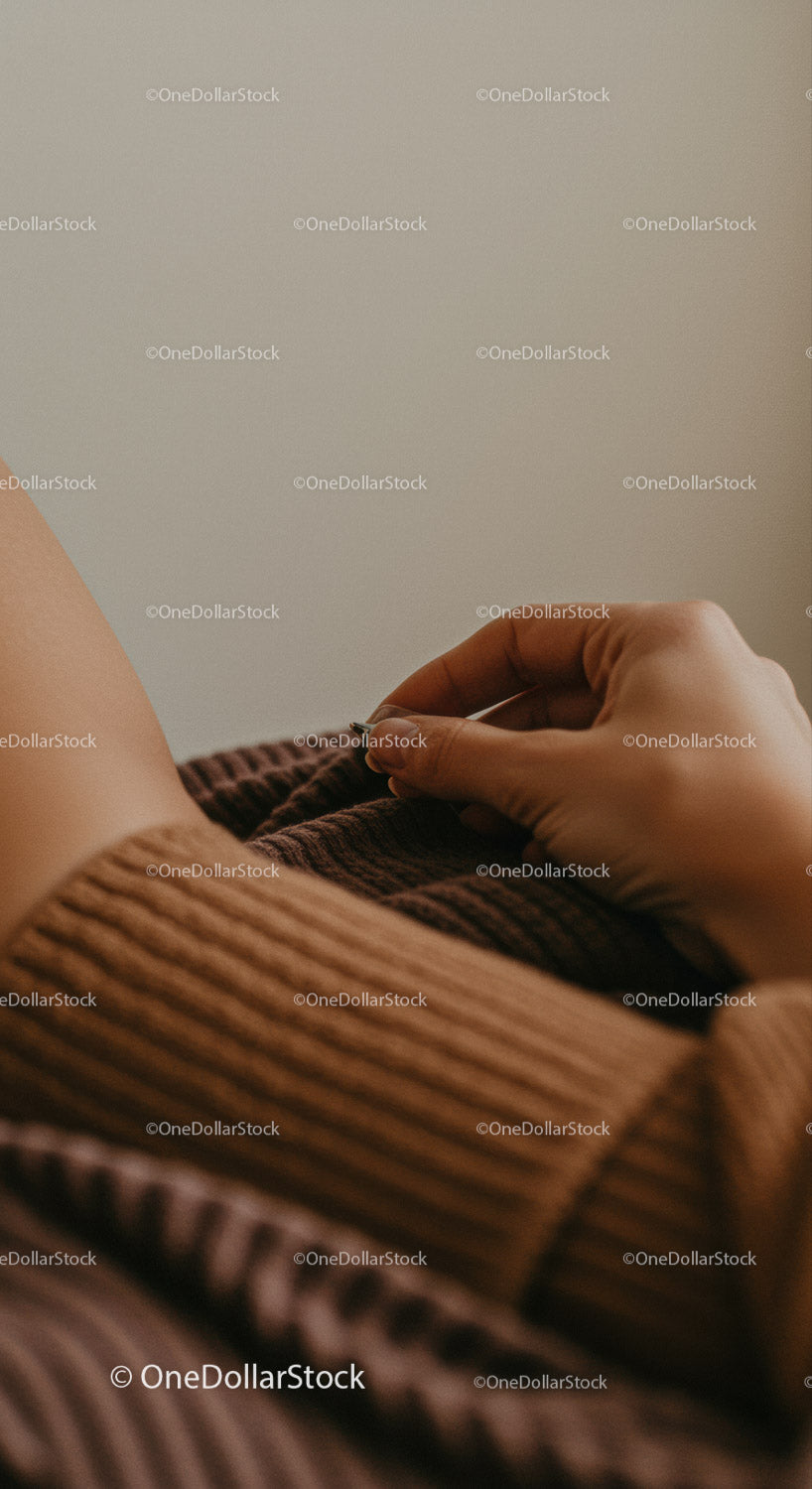 Close-up of a hand resting on a cozy brown ribbed sweater in a warm atmosphere