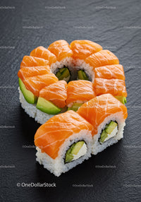 Fresh salmon and avocado sushi roll on black surface