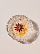 Glass bowl with ice and star anise on light surface