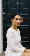 Elegant woman in white dress sitting by navy door