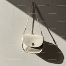 Elegant white leather handbag hanging on wall