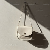 Elegant white leather handbag hanging on wall