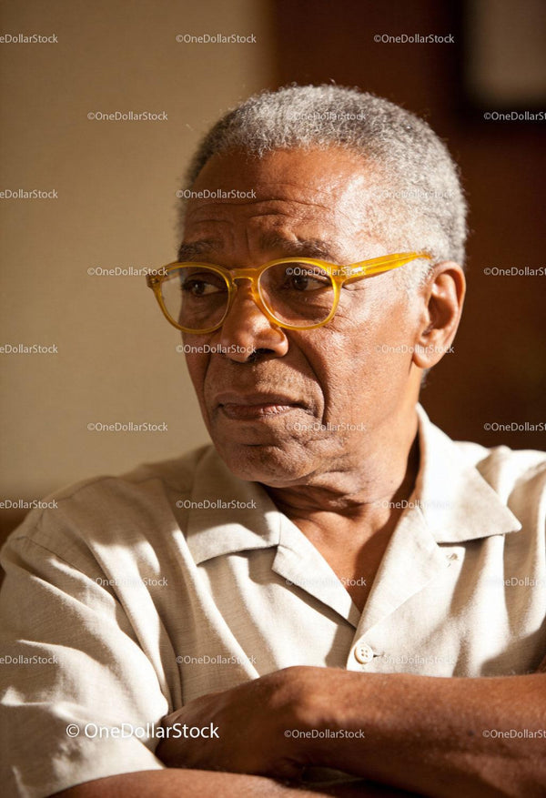 Elderly man wearing yellow glasses in thoughtful mood