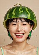 Smiling woman wearing fresh watermelon helmet with water drops