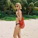 Stylish Young Woman in Bikini with Red Net Bag on Tropical Beach