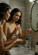 Women Applying Skincare Serum in Modern Bathroom