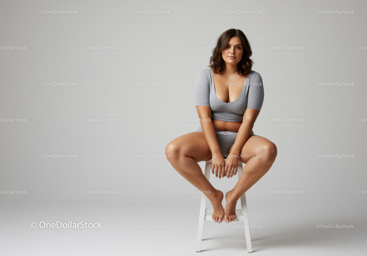 Confident Woman in Casual Grey Outfit Sitting on a White Stool