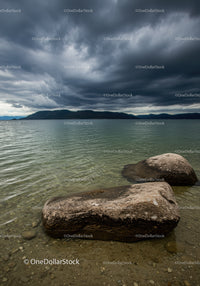 Calm lake shore under dramatic stormy sky