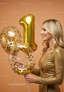 Smiling woman celebrating with gold number balloons