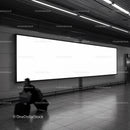 Traveler walking past large blank billboard in subway station