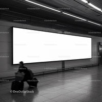 Traveler walking past large blank billboard in subway station