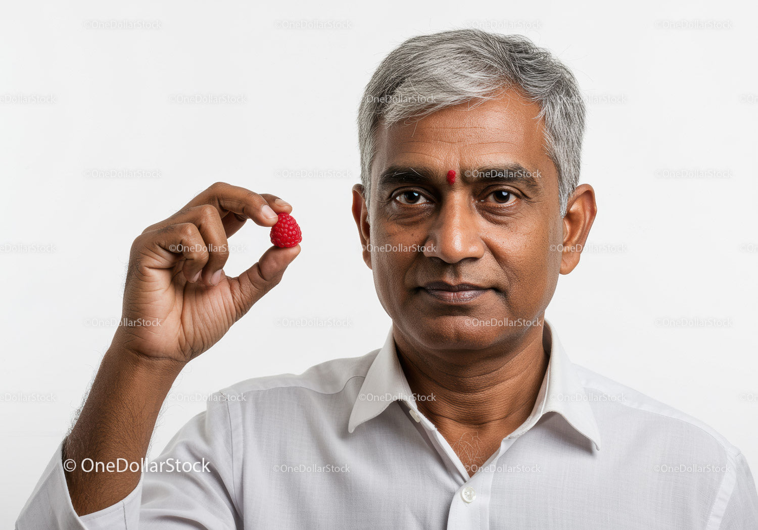 Pewny siebie Hindus trzymający malinę w jasnym portrecie studyjnym