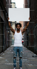 Young Man Holding Blank Sign in Urban Alleyway