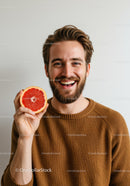 Cheerful Man Holding Juicy Pink Grapefruit with a Bright Smile