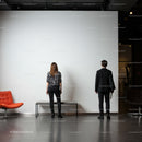Two people admiring blank white gallery wall indoors
