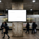 Urban commuters passing by blank billboard in metro station