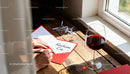 Writing a Love Note by the Window with Red Wine Glass
