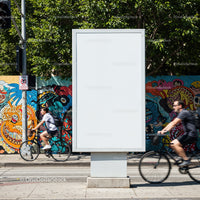 Empty urban billboard with cyclists passing vibrant mural