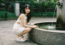 Young Woman Wearing White Dress and Platform Sandals by Water Fountain