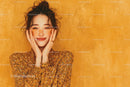 Joyful Woman with Freckles and Curly Hair in Floral Dress on Orange Background
