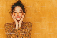 Joyful Woman with Freckles and Curly Hair in Floral Dress on Orange Background