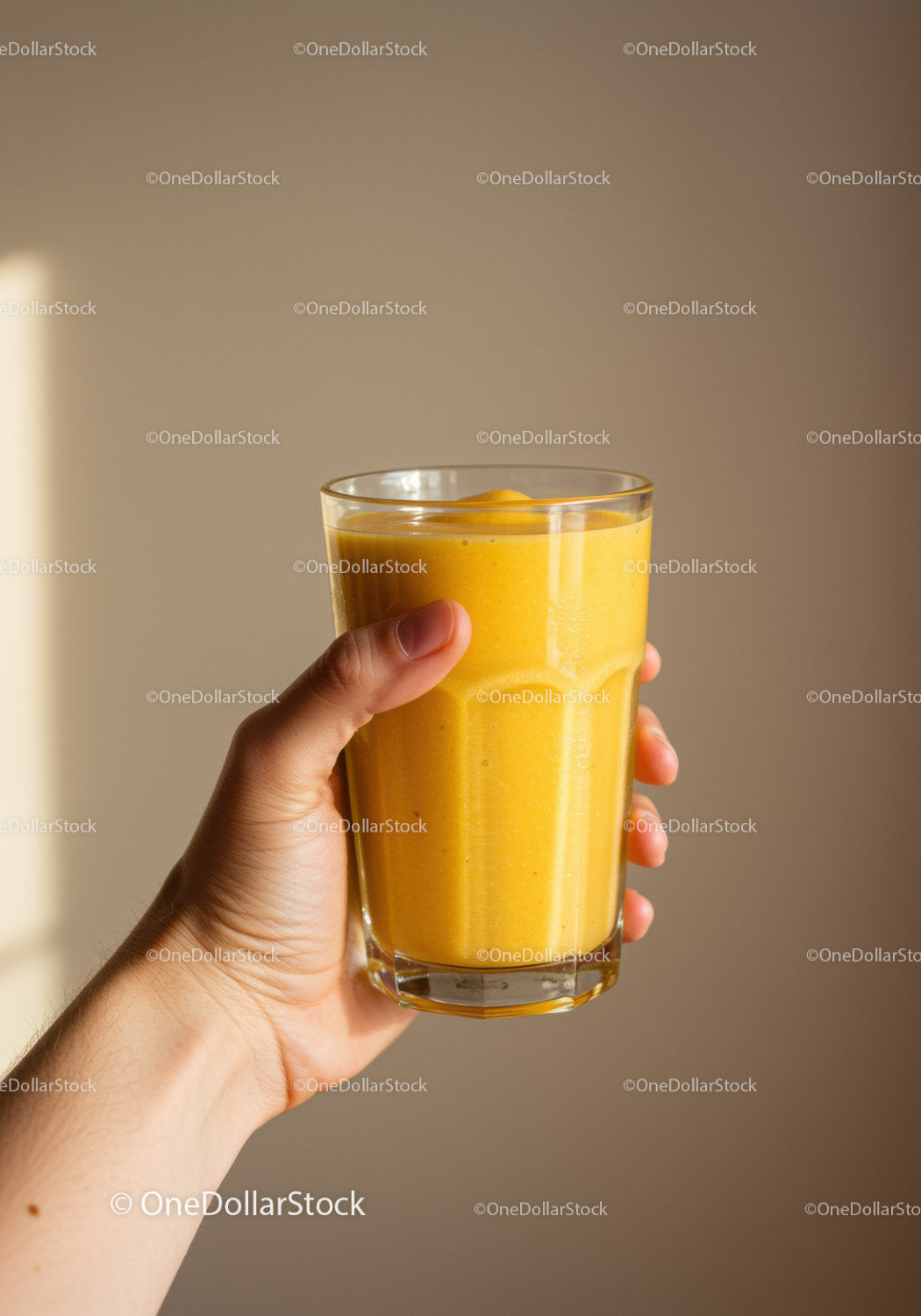 Hand Holding Glass of Fresh Yellow Smoothie