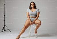 Young Woman in Gray Sportswear Sitting on Stool in Indoor Studio