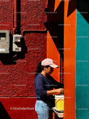 Woman Preparing Food Outside Colorful Urban Wall