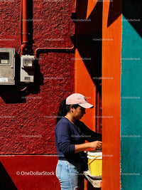 Woman Preparing Food Outside Colorful Urban Wall