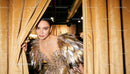 Elegant woman in feathered evening gown peeking behind curtains