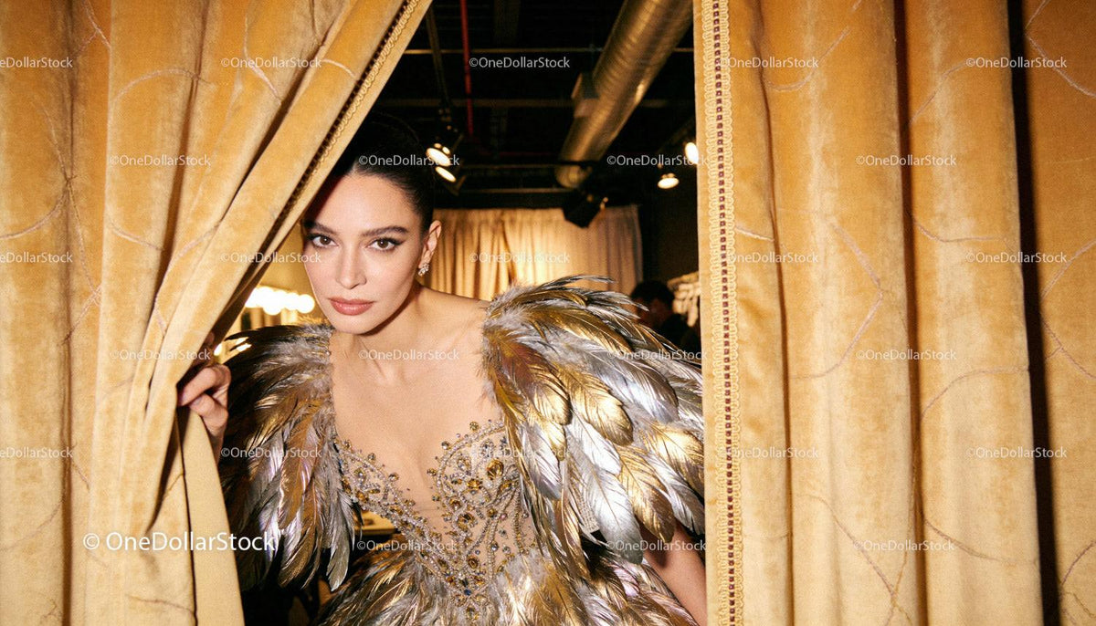 Elegant woman in feathered evening gown peeking behind curtains