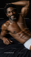 Smiling muscular man relaxing on black bedding