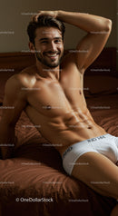 Smiling muscular man relaxing on brown bed sheets