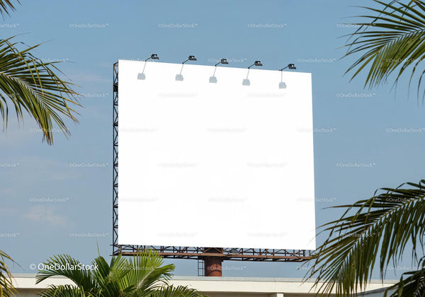 Blank billboard outdoors framed by tropical palm leaves JPG Mockup Image