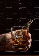 Hand Holding Glass of Whiskey with Splashing Ice Cubes