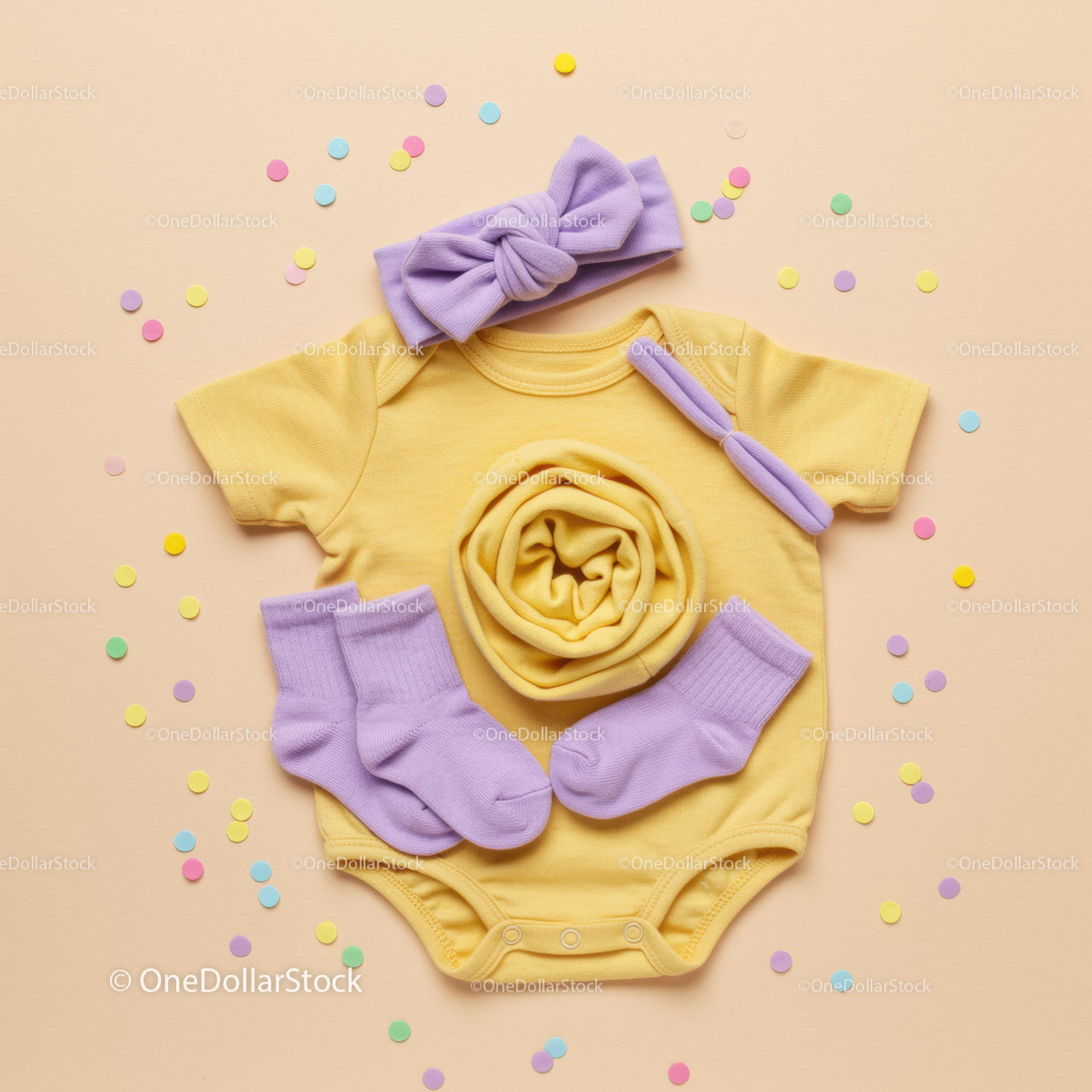 Yellow Baby Onesie with Lilac Accessories on Beige Background