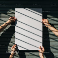 Hands holding blank white paper with shadows on metal background
