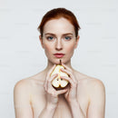 Elegant Redhead Woman Holding Pear in Front of White Background