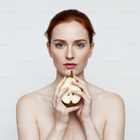 Elegant Redhead Woman Holding Pear in Front of White Background