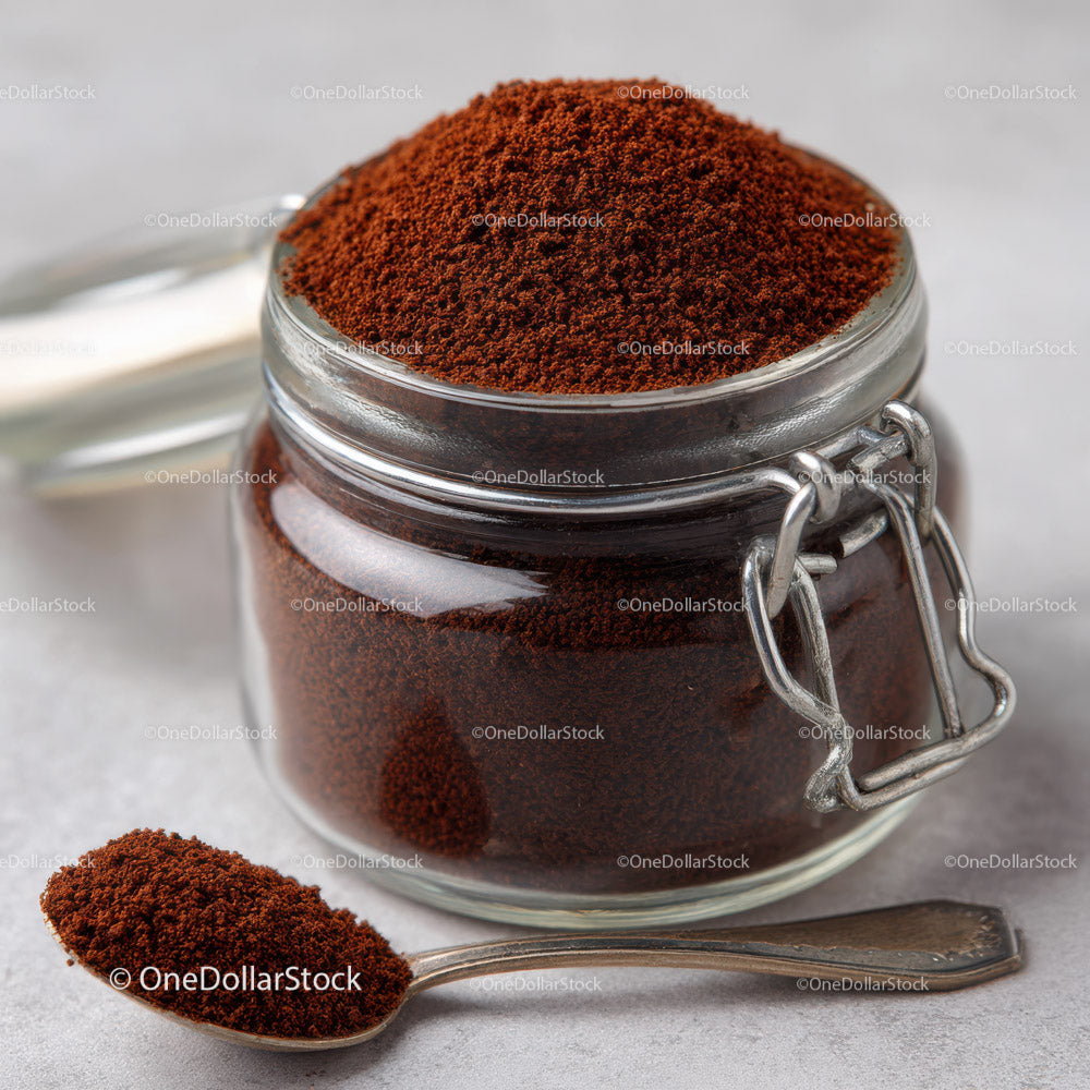 Glass Jar of Ground Coffee with Silver Spoon on Light Surface